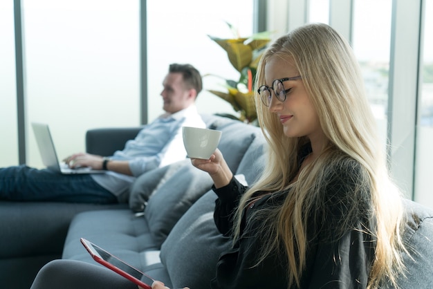 Yung couple in casual look enjoy social network and playing game from tablet stay together at home.