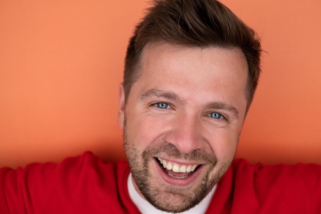 Yyoung man smiling while standing isolated on orange background