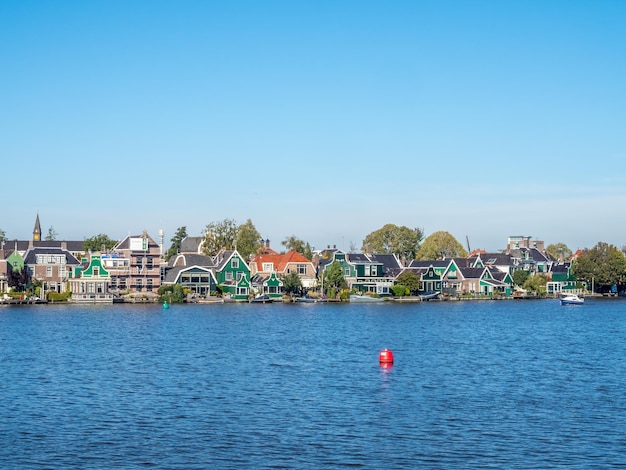 Zaan Schans is popular attractions in Netherlands, has a collection of well-preserved historic windmills and houses, this view from bridge under blue sky