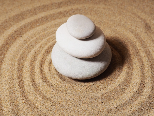 Zen garden. Pyramids of white and gray zen stones on the white sand with abstract wave drawings.