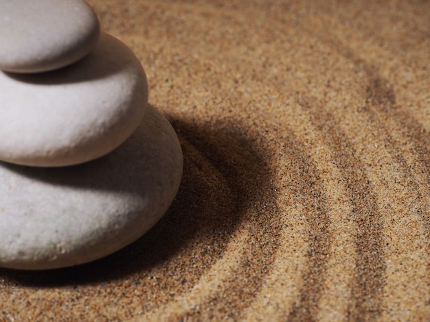 Zen garden. Pyramids of white and gray zen stones on the white sand with abstract wave drawings.