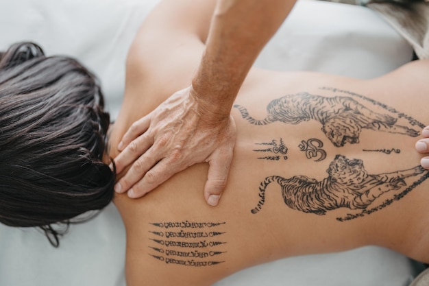 Zenith view of a masseur39s hand pressing on a woman39s tattooed upper back