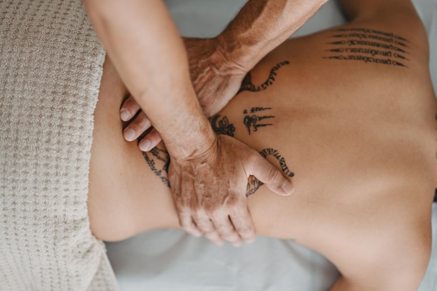 Zenithal view of a masseur39s hands on a woman39s back with tattoos