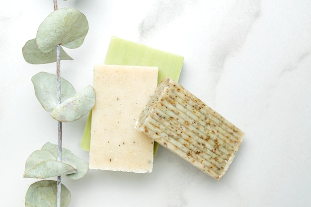 Zero waste cosmetics concept Flat lay top view of natural organic solid handmade soap and eucalyptus plant near it on marble background