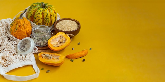 Zero waste healthy food pumpkin, seeds, vegetables, dried fruits flat lay on orange background. Groceries in textile bags,glass jars. Eco friendly plastic free low waste lifestyle.