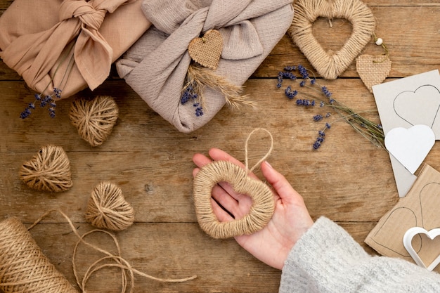 Zero waste Valentine's Day concept and mock up. gift packaged furoshiki style with lavender, pampas grass jute and stencil hearts. Top view or flat lay. Instruction, step by step