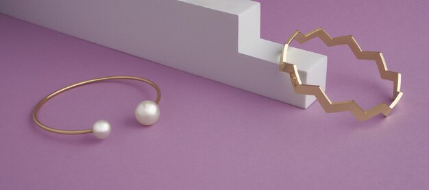 Zigzag shape and modern golden with pearls bracelets on white and purple background