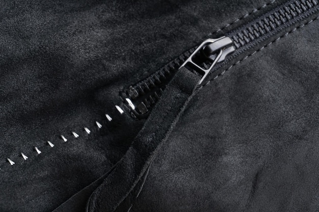 Zip with a tab on a black suede jacket with white contrasting seams