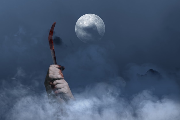 Zombie hands with wound holding sickle with the night scene background