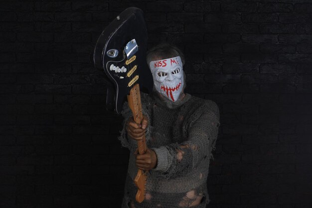 A zombie with a mask that says kiss me and a guitar.