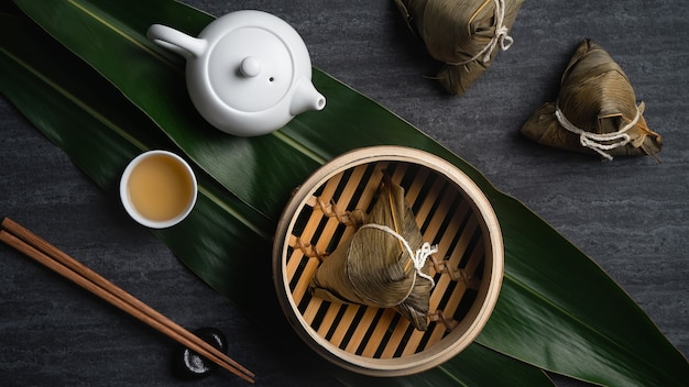 Zongzi rice dumpling top view for Chinese traditional Dragon Boat Festival (Duanwu Festival) over dark black slate background.