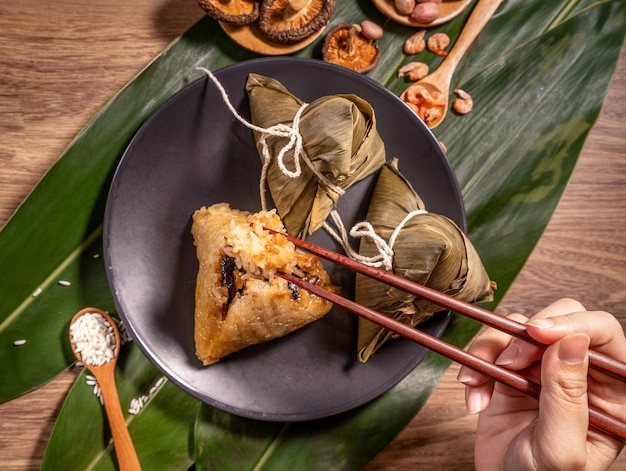 Zongzi woman eating steamed rice dumplings on wooden table food in dragon boat festival duanwu concept close up copy space top view flat lay