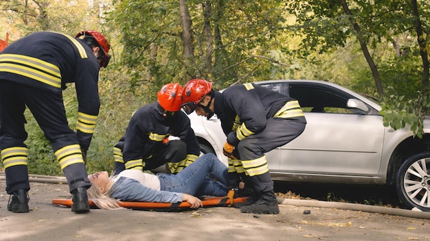 Zoom in view of mature female victim watching firefighters extinguishing fire on burning vehicle after car crash