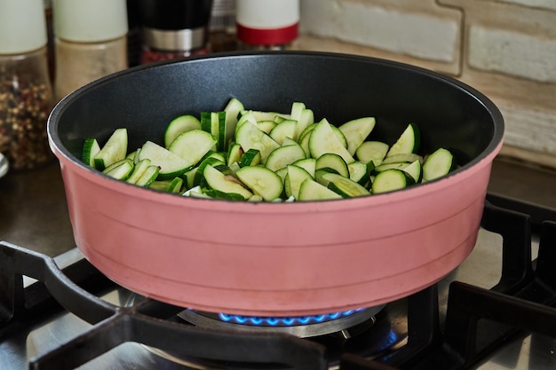 Zucchini cut into half rings are fried in pan on gas stove