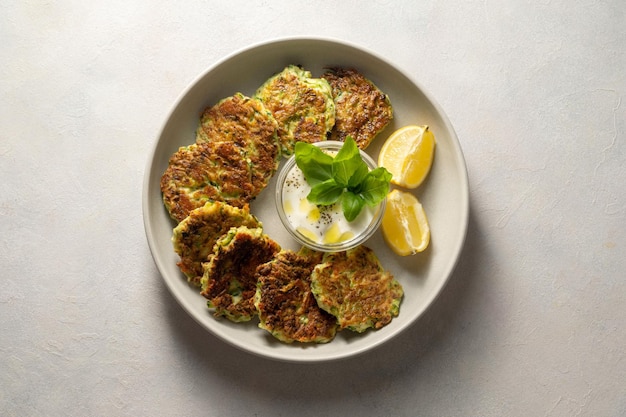 Zucchini fritters or vegetarian zucchini pancakes served with yogurt sauce