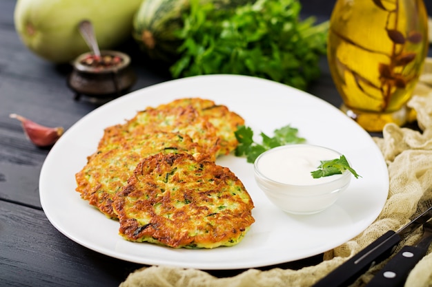 Zucchini pancakes with parsley on a wooden table.