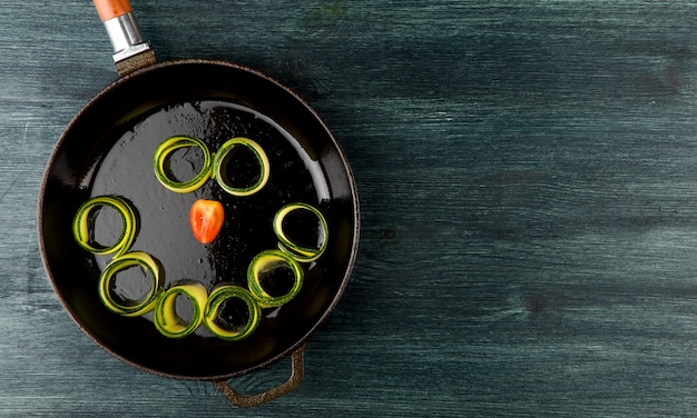 Zucchini in the table. Fried young sliced courgettes in a pan on a dark table. The view from the top. Copy space