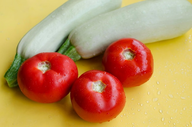 Zucchini and tomatoes on a yellow background closeup