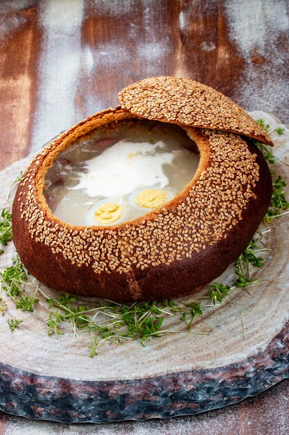 Zurek sour soup made of rye flour with sausage and egg served in bread bowl Popular Easter dish