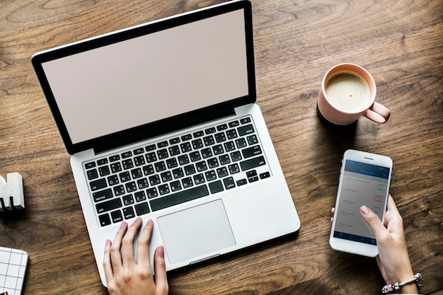 Aerial view of woman using computer laptop and a smartphone on wooden table