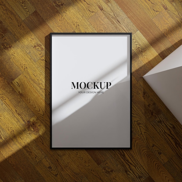 Aesthetic frame mockup poster laying on the wooden floor lit by sunlight