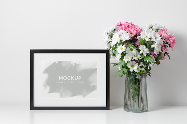 Artwork frame mockup with flowers bouquet in white room interior