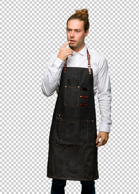 Barber man in an apron having doubts while looking up