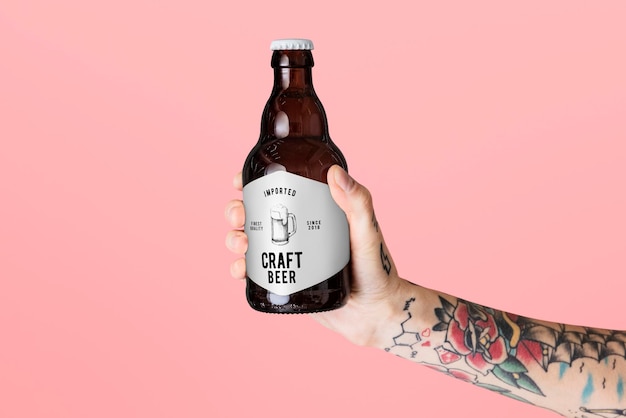 Beer label mockup. Tattooed hand holding bottle of craft beer.