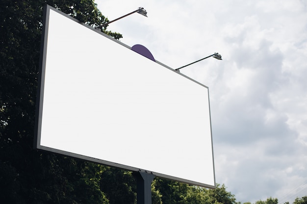 Bilbard with multi-colored advertising and illumination stands on the street in daylight, photo below