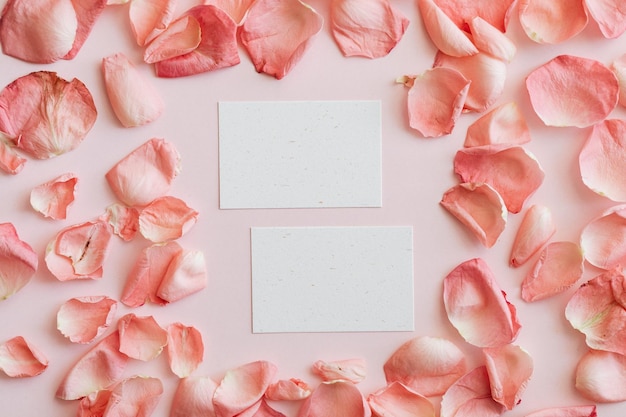 Blank business cards mockup with light pink background and pink rose petals