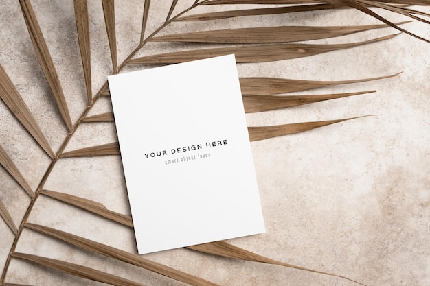 Blank invitation or greeting card mockup with dry palm tree leaf decor