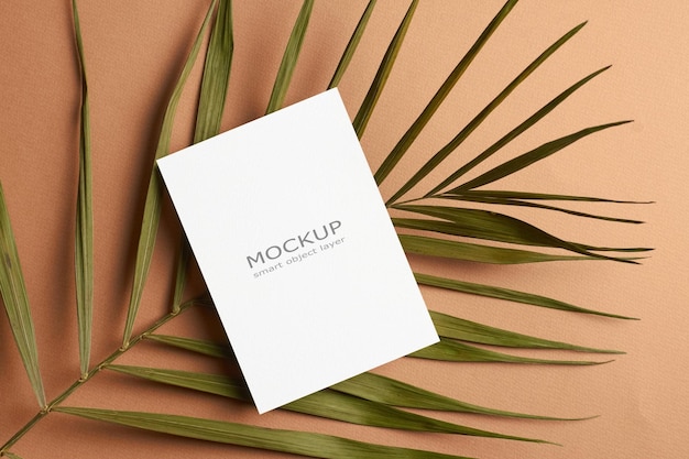 Blank invitation or greeting card mockup with palm tree leaf