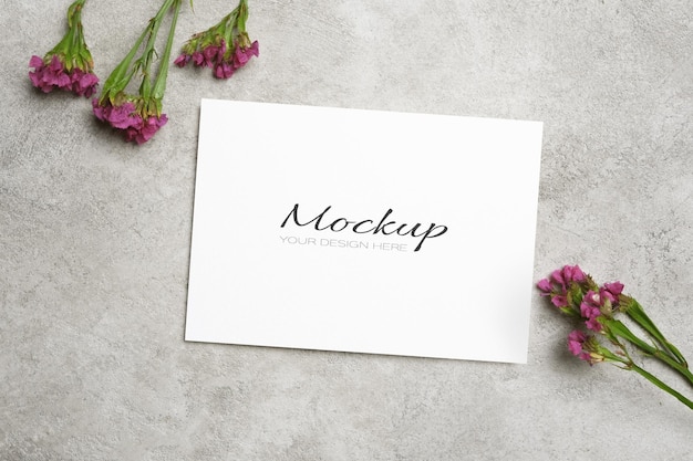 Blank invite card mockup with flowers decor on grey