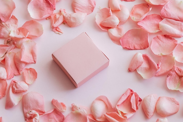 Blank pink box packaging design mockup with light pink background and pink rose petals