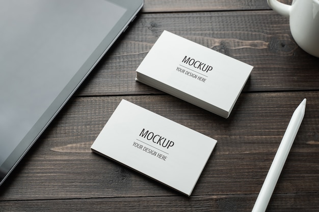 Blank white Business card mockup PSD and tablet with stylus pencil on wood table 