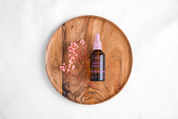 a bottle of perfume sits on a wooden plate with a pink flower in the middle