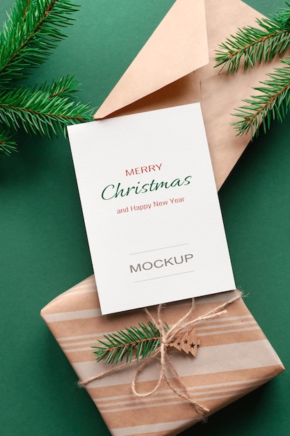 Christmas greeting card mockup with envelope gift box and green fir tree branches