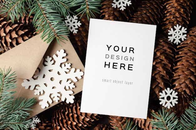 Christmas greeting card mockup with envelope, snowflakes decorations and fir tree branches and cones