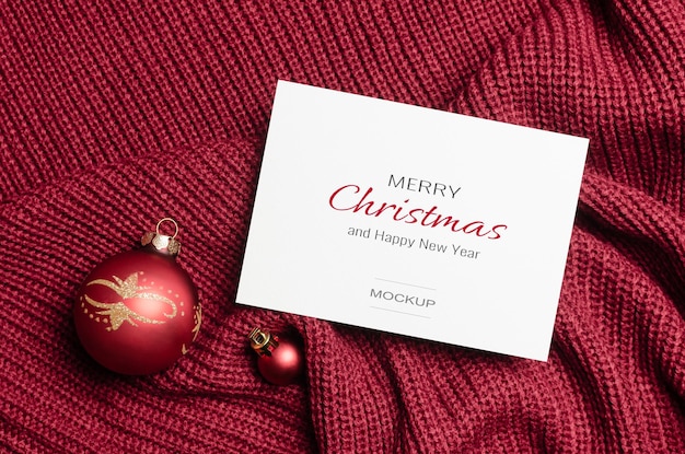 Christmas greeting card mockup with red balls decorations on knitted background