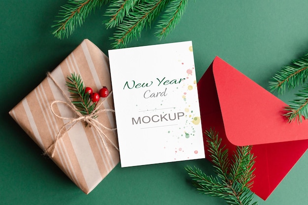 Christmas greeting card mockup with red envelope gift box and green fir tree branches