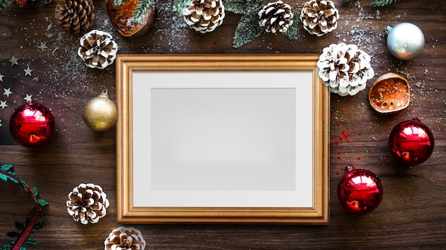 Classic gold frame mockup with Christmas decorations on wooden background