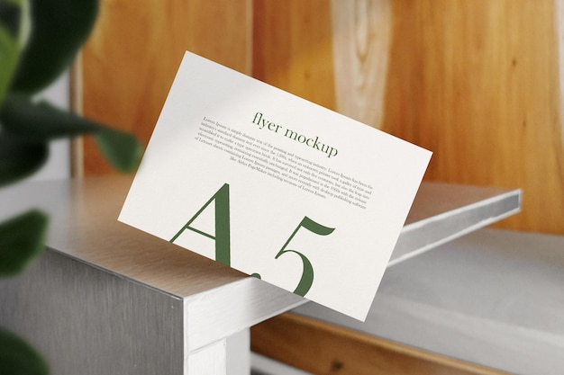 Clean minimal A5 flyer mockup on top table background with leaves PSD file