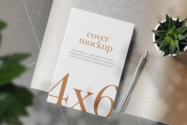 Clean minimal book 4x6 mockup on top table with plant and pen background PSD file