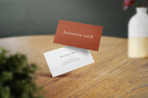 Clean minimal business card mockup floating on desk background with vase and plant foreground