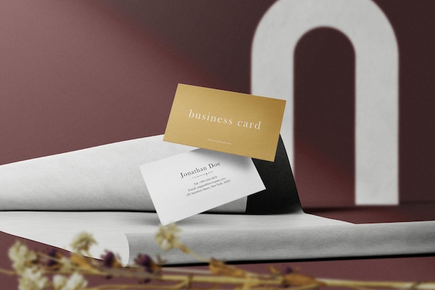 Clean minimal business card mockup floating on paper fold with dry plant