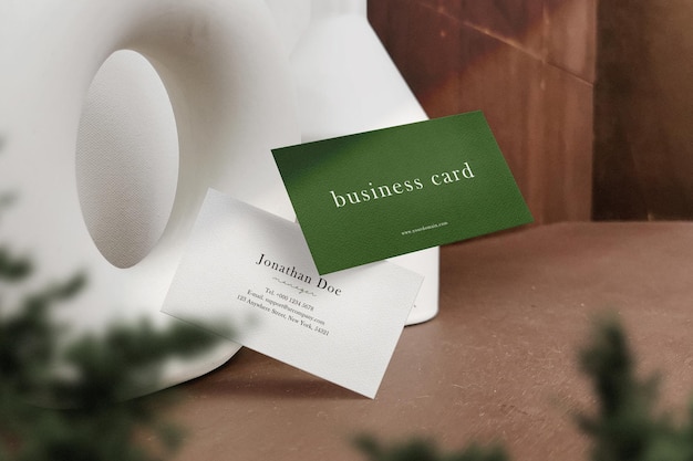 Clean minimal business card mockup floating on table with plant background PSD file