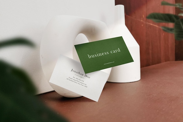 Clean minimal business card mockup floating on table with plant background PSD file