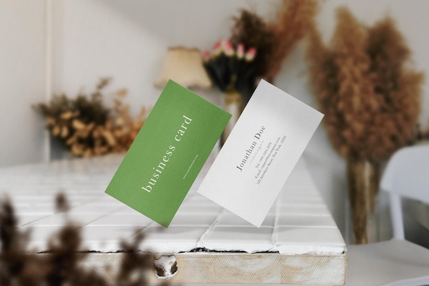 Clean minimal business card mockup floating on top white table with plant