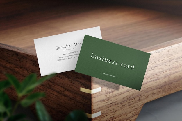 Clean minimal business card mockup floating on wooden plate with leaves.