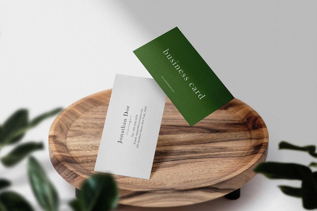 Clean minimal business card mockup floating on wooden plate with leaves